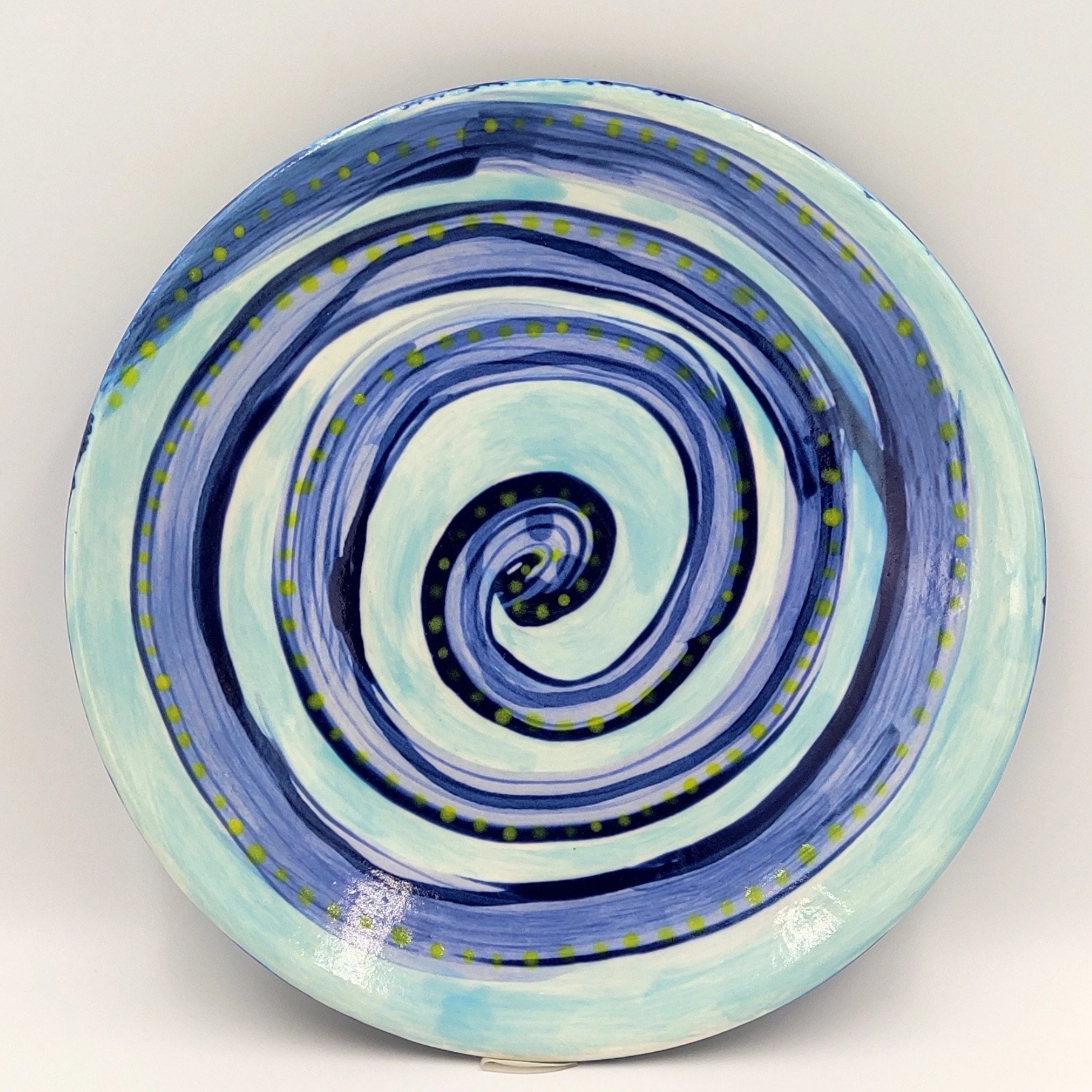malowanie-ceramiki-gdansk-talerz19cm-spirala-niebiesko-turkusowa Talerz ceramiczny z warsztatów malowania ceramiki w Gdańsku ozdobiony spiralnym wzorem w odcieniach niebieskiego i turkusowego z żółtymi kropkami podkreślającymi wzór. Efektowna ceramika ręcznie malowana podczas kreatywnych warsztatów w Gdańsku.