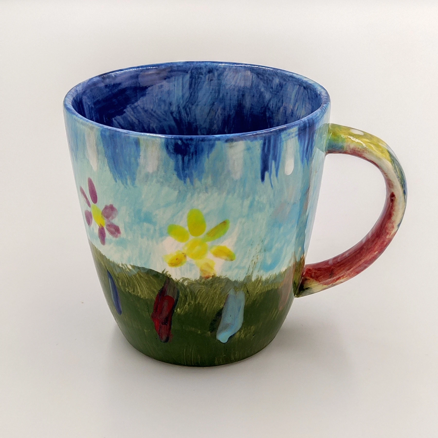 malowanie_ceramiki_gdansk_kubek038l_wiosenny_kwiaty Kolorowy kubek 0,38l z motywem kwiatowym i niebieskim tłem z zajęć malowania ceramiki w Gdańsku